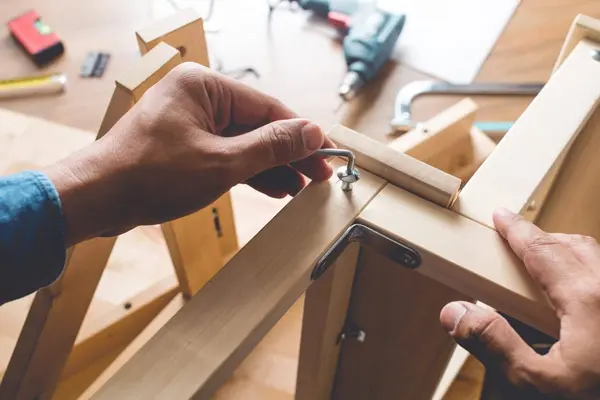 Hands Repairing Wooden Furniture Frame with Tools Nearby