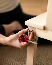 Craftsman upholstering a fabric sofa in a well-lit home workshop